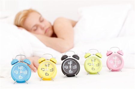 Beautiful young woman is sleeping in the bed, with many alarm clocks in the front Foto de stock - Royalty-Free Super Valor e Assinatura, Número: 400-04384711
