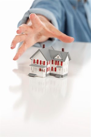 Womans Hand Reaching for Model House on a White Surface. Stock Photo - Budget Royalty-Free & Subscription, Code: 400-04384910
