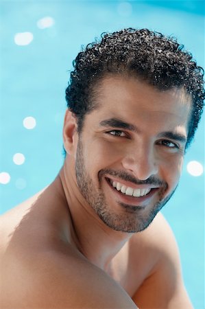 simsearch:400-04391064,k - Handsome happy young hispanic man smiling and relaxing near hotel pool. Vertical shape, head and shoulders Stock Photo - Budget Royalty-Free & Subscription, Code: 400-04386586
