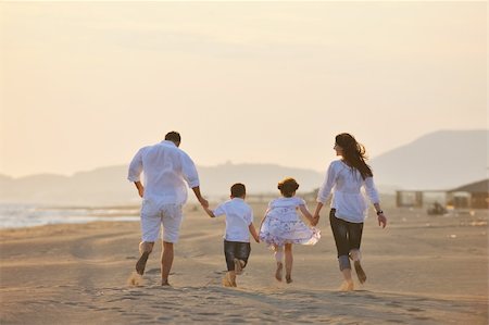 happy young family have fun on beach run and jump  at sunset Stock Photo - Budget Royalty-Free & Subscription, Code: 400-04389574