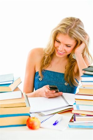 simsearch:700-00185645,k - Smiling young girl reading sms on mobile instead of doing homework Photographie de stock - Aubaine LD & Abonnement, Code: 400-04380505