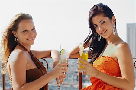 young caucasian female couple drinking cocktails and looking at camera on terrace in Havana, Cuba. Horizontal shape, waist up, side view Stock Photo - Budget Royalty-Free & Subscription, Code: 400-04381110