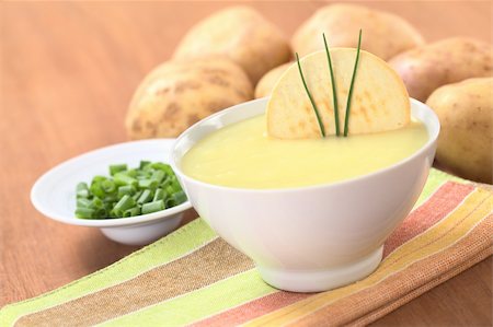 soup and crackers - Fresh potato cream soup garnished with a cracker and chives with green onion and raw potatoes in the back on wood (Selective Focus, Focus on the cracker and the chives) Stock Photo - Budget Royalty-Free & Subscription, Code: 400-04381975