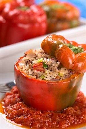Baked stuffed red bell pepper filled with minced meat, onion, rice, tomato and green onion served on tomato sauce with casserole in the back (Selective Focus, Focus on the tomato piece and the stuffing around it on the top) Stock Photo - Budget Royalty-Free & Subscription, Code: 400-04381981