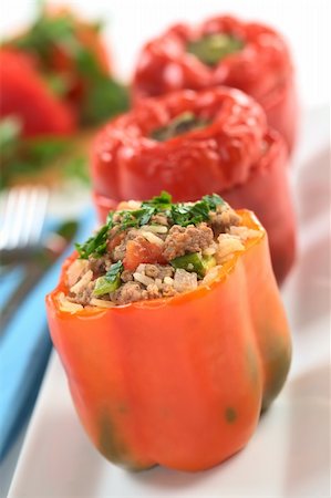 Baked stuffed red bell pepper filled with ground meat, onion, rice, tomato and green onion garnished with parsley served on a long plate (Selective Focus, Focus on the tomato piece and the stuffing around it on the top) Stock Photo - Budget Royalty-Free & Subscription, Code: 400-04381991