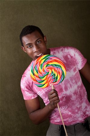 funny sweets - Smiling African-American male bites into a giant lollipop Stock Photo - Budget Royalty-Free & Subscription, Code: 400-04382065