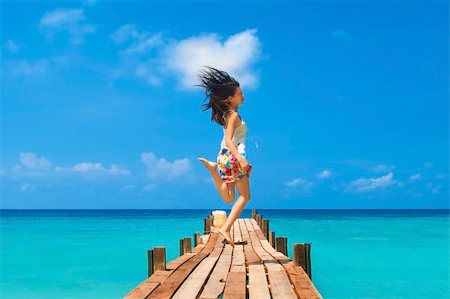 Pretty young girl is jumping up in the air at the beach jetty Stock Photo - Budget Royalty-Free & Subscription, Code: 400-04382270