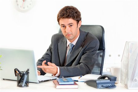 simsearch:400-06639907,k - Modern business man sitting at office desk and pointing finger on laptop Stock Photo - Budget Royalty-Free & Subscription, Code: 400-04382799