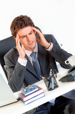 simsearch:400-05900668,k - Modern businessman with headache sitting at office desk and holding hands at head Stock Photo - Budget Royalty-Free & Subscription, Code: 400-04382793