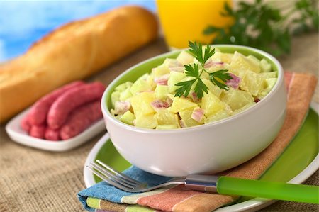 simsearch:400-04855321,k - Potato salad made of cooked potatoes, red onions and cucumber, seasoned with a mayonnaise dressing and garnished with a parsley leaf with sausages, baguette and orange juice in the back (Selective Focus, Focus on the front of the salad and the leaf) Stock Photo - Budget Royalty-Free & Subscription, Code: 400-04394324