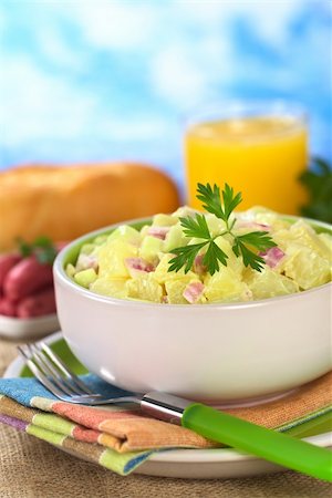 Potato salad made of cooked potatoes, red onions and cucumber, seasoned with a mayonnaise dressing and garnished with a parsley leaf (Selective Focus, Focus on the front of the salad and the leaf) Foto de stock - Super Valor sin royalties y Suscripción, Código: 400-04394323