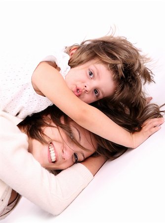 A portrait of a mother and her baby girl lying on the floor and playing over white background Stock Photo - Budget Royalty-Free & Subscription, Code: 400-04395533