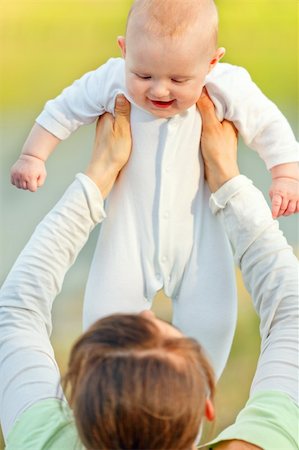 simsearch:400-06076022,k - Mother holding laughing baby girl in hands outdoors at summer day. Close up. Photographie de stock - Aubaine LD & Abonnement, Code: 400-04396165