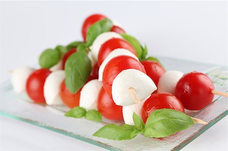 Cherry tomatoes and mozzarella on skewers, garnished with basil leaves and olive oil Stock Photo - Budget Royalty-Free & Subscription, Code: 400-04399998