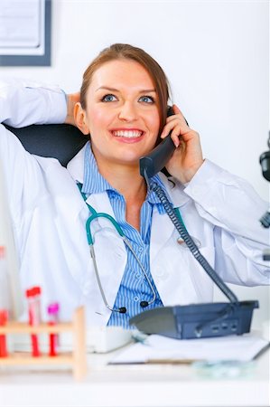 simsearch:400-04390415,k - Relaxed  medical doctor woman sitting at office table and talking on phone Stock Photo - Budget Royalty-Free & Subscription, Code: 400-04390409