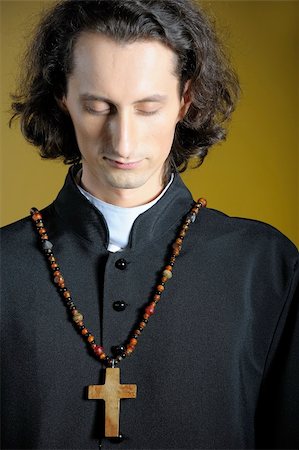 evangelist - conceptual portrait of Praying priest with wooden cross praying. yellow background Photographie de stock - Aubaine LD & Abonnement, Code: 400-04390870