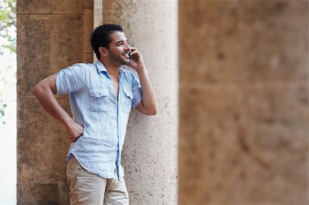 simsearch:400-04391064,k - mid adult hispanic man talking on mobile phone and leaning on columns outdoors. Horizontal shape, side view, copy space Stock Photo - Budget Royalty-Free & Subscription, Code: 400-04391067