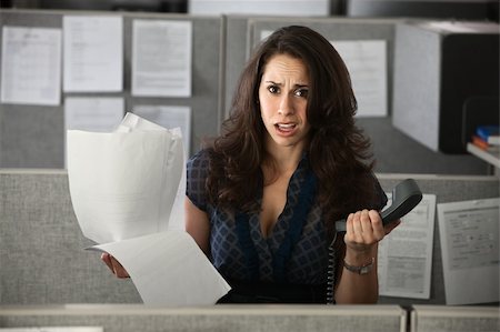 Confused female employee holds documents and a telephone Stock Photo - Budget Royalty-Free & Subscription, Code: 400-04391517