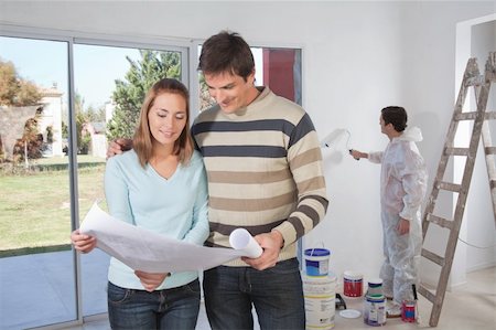 Couple going through house plan while painter in the background Stock Photo - Budget Royalty-Free & Subscription, Code: 400-04393264