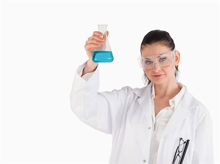 Dark-haired scientist holding a blue flask while looking at the camera Stock Photo - Budget Royalty-Free & Subscription, Code: 400-04405823