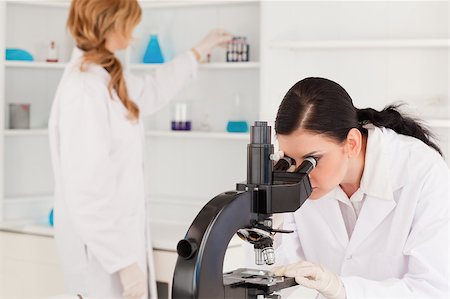 Dark-haired scientist looking through a microscope with her assistant in a lab Stock Photo - Budget Royalty-Free & Subscription, Code: 400-04405875