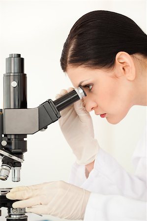 simsearch:400-05670345,k - Scientist conducting an experiment looking through a microscope in a lab Photographie de stock - Aubaine LD & Abonnement, Code: 400-04405893