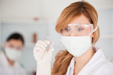 Blond-haired scientist wearing a mask and safety glasses and holding a  test tube in a lab Stock Photo - Budget Royalty-Free & Subscription, Code: 400-04405903