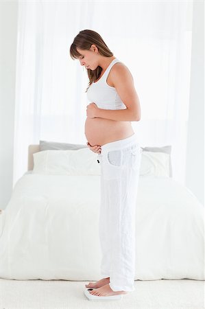 Attractive pregnant female using a scale while standing in her bedroom Stock Photo - Budget Royalty-Free & Subscription, Code: 400-04406083