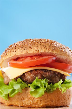 simsearch:400-06513131,k - Cheeseburger with tomatoes and lettuce on a wooden table with blue background Stock Photo - Budget Royalty-Free & Subscription, Code: 400-04406560