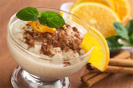 Delicious homemade rice pudding with cinnamon garnished with orange peel and mint leaf and a slice of orange on the rim of the bowl (Selective Focus, Focus on the orange peel and parts of the mint leaf as well as the upper part of the orange slice on the rim) Stock Photo - Budget Royalty-Free & Subscription, Code: 400-04407891