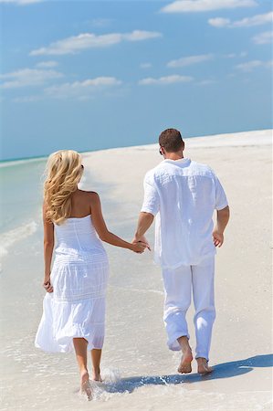 running marriage - Happy young man and woman couple running or walking and holding hands on a deserted tropical beach with bright clear blue sky Stock Photo - Budget Royalty-Free & Subscription, Code: 400-04408390