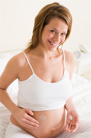 Pregnant woman in bedroom rubbing cream on belly smiling Stock Photo - Budget Royalty-Free & Subscription, Code: 400-04400454