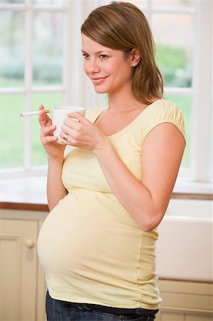 pregnant smoking photos - Pregnant woman standing in kitchen with coffee and cigarette smi Stock Photo - Budget Royalty-Free & Subscription, Code: 400-04400505