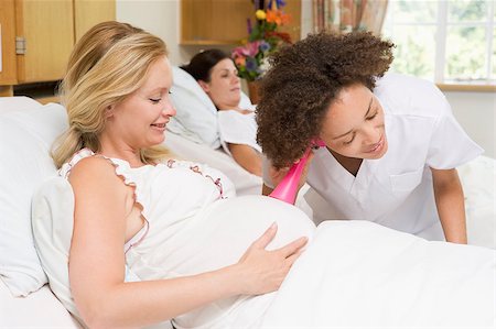 Nurse checking pregnant woman's belly and smiling Stock Photo - Budget Royalty-Free & Subscription, Code: 400-04400706
