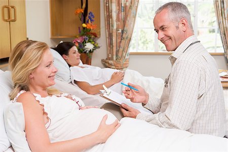 Doctor talking to pregnant woman holding chart and smiling Stock Photo - Budget Royalty-Free & Subscription, Code: 400-04400707