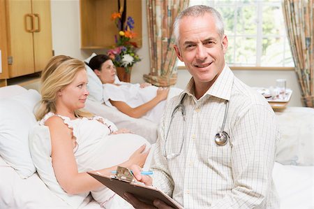 Doctor sitting by pregnant women holding chart and smiling Stock Photo - Budget Royalty-Free & Subscription, Code: 400-04400708
