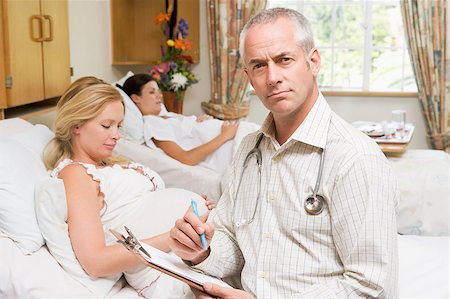 Doctor sitting by pregnant women holding chart Stock Photo - Budget Royalty-Free & Subscription, Code: 400-04400709