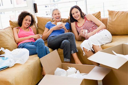 Three girl friends relaxing with coffee by boxes in new home smi Stock Photo - Budget Royalty-Free & Subscription, Code: 400-04400839