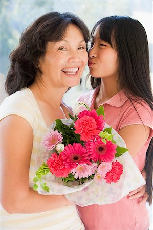 Granddaughter kissing grandmother on cheek holding flowers and s Stock Photo - Budget Royalty-Free & Subscription, Code: 400-04401506