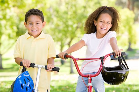 simsearch:400-04402106,k - Brother and sister outdoors with scooter and bicycle smiling Fotografie stock - Microstock e Abbonamento, Codice: 400-04402041