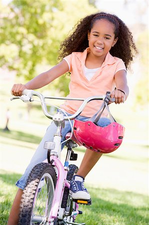 simsearch:400-04402106,k - Young girl on bicycle outdoors smiling Fotografie stock - Microstock e Abbonamento, Codice: 400-04402098