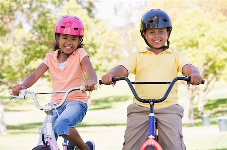 simsearch:400-04402106,k - Brother and sister outdoors on bicycles smiling Fotografie stock - Microstock e Abbonamento, Codice: 400-04402091