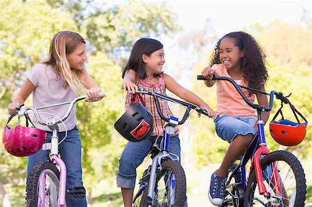 Three young girl friends outdoors on bicycles smiling Stock Photo - Budget Royalty-Free & Subscription, Code: 400-04402103