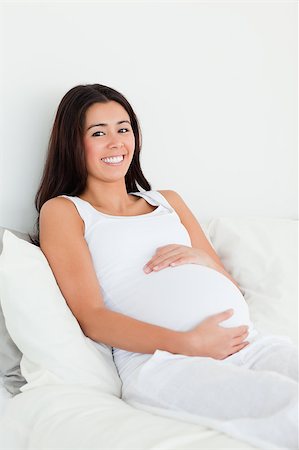 simsearch:400-04414996,k - Frontal view of a pretty pregnant woman touching her belly while lying on a bed at home Stock Photo - Budget Royalty-Free & Subscription, Code: 400-04414947