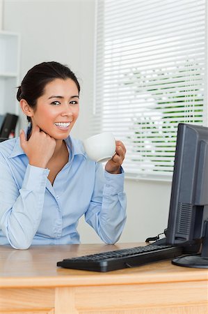 simsearch:400-04188263,k - Beautiful woman enjoying a cup of coffee while looking at a computer screen at the office Foto de stock - Super Valor sin royalties y Suscripción, Código: 400-04414974