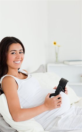 simsearch:400-04414996,k - Attractive pregnant woman putting headphones on her belly while lying on a bed at home Stock Photo - Budget Royalty-Free & Subscription, Code: 400-04414986