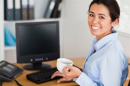 simsearch:400-04188263,k - Beautiful woman holding a cup of coffee while sitting at the office Foto de stock - Super Valor sin royalties y Suscripción, Código: 400-04415004