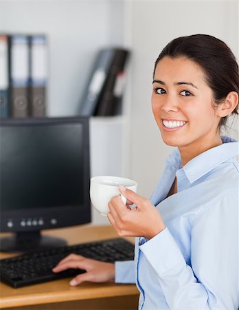 simsearch:400-04188263,k - Pretty woman holding a cup of coffee while sitting at the office Foto de stock - Super Valor sin royalties y Suscripción, Código: 400-04415005