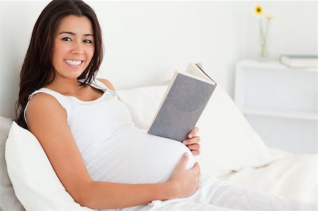 pregnant mom reading - Beautiful pregnant woman reading a book while lying on a bed at home Stock Photo - Budget Royalty-Free & Subscription, Code: 400-04415041
