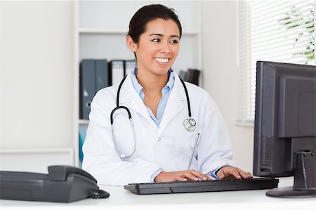 simsearch:400-05350424,k - Attractive woman doctor typing on a keyboard in her office Foto de stock - Super Valor sin royalties y Suscripción, Código: 400-04415050